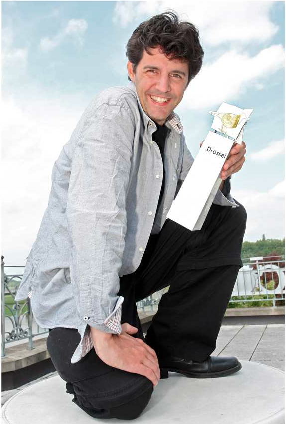 Roger Stein kniet lächelnd mit der Trophäe der Meißner Drossel