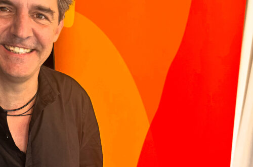 Roger Stein lächelnd vor dem Banner von Deutschlandfunk Kultur im Funkhaus Berlin