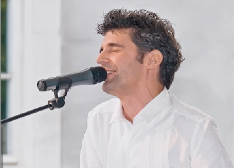 Roger Stein im weissen Hemd singt lächelnd mit geschlossenen Augen ins Mikrofon