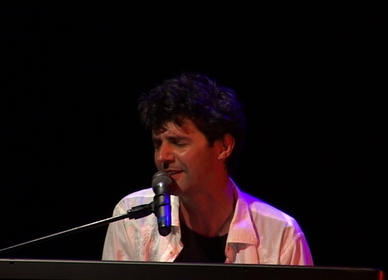 Roger Stein singt mit geschlossenen Augen am Keyboard, dunkler Bühnenhintergrund