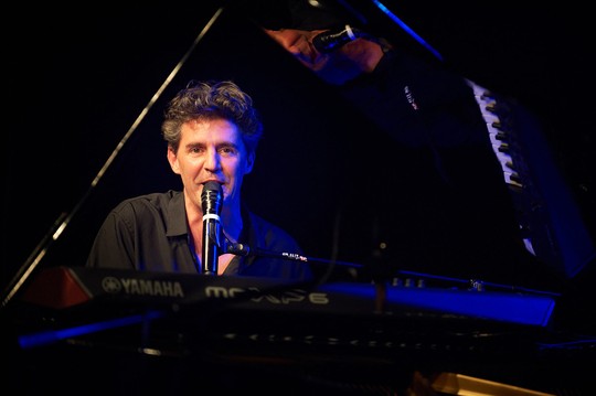 Roger Stein singt am Flügel mit Keyboard, blau beleuchtet
