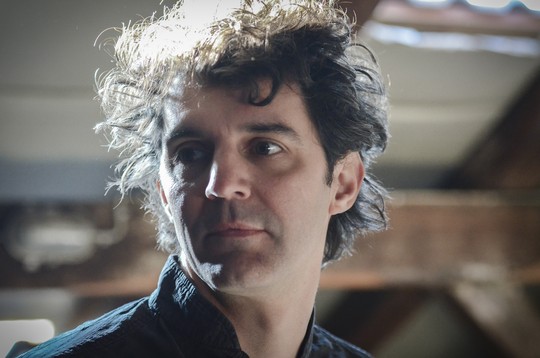 Porträt von Roger Stein mit lockigem Haar im Gegenlicht, Blick zur Seite