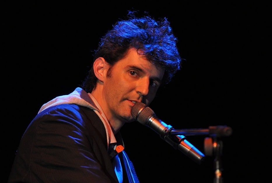 Roger Stein am Mikrofon, blaues Bühnenlicht