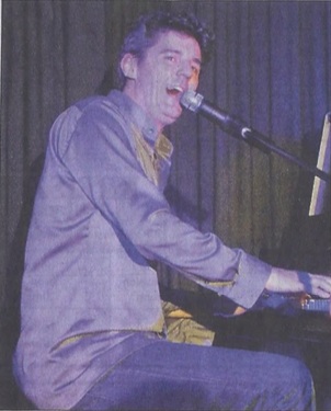 Roger Stein singt mit offenem Mund am Klavier ins Mikrofon