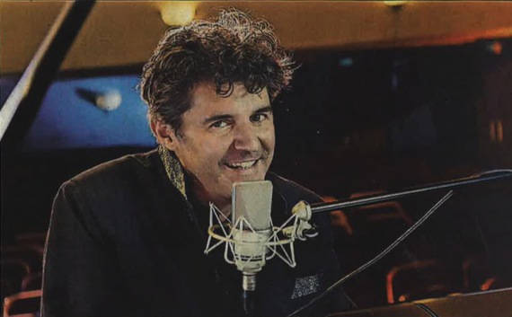Roger Stein lächelt am Flügel hinter einem Studiomikrofon