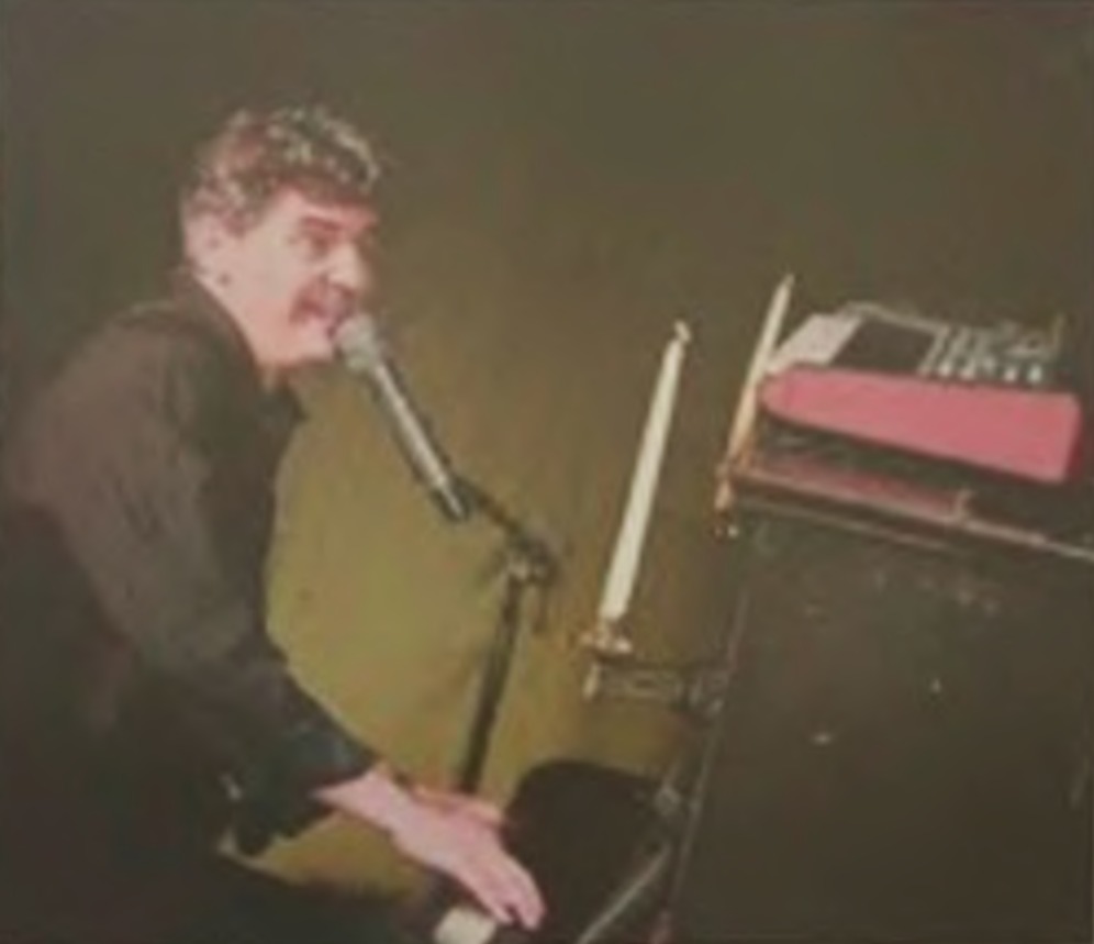 Roger Stein singt am Klavier, neben ihm eine Kerze und ein rotes Keyboard